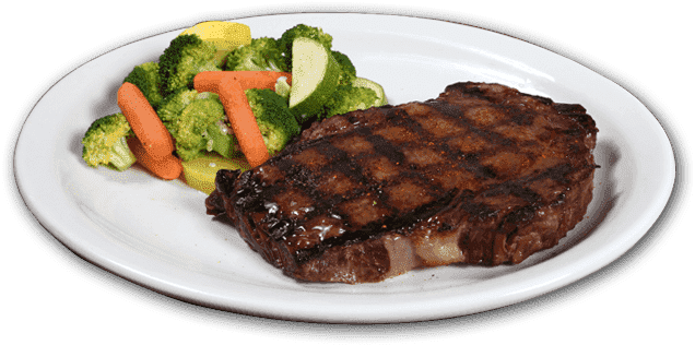 Steak with broccoli, carrots, and zucchini on a white plate